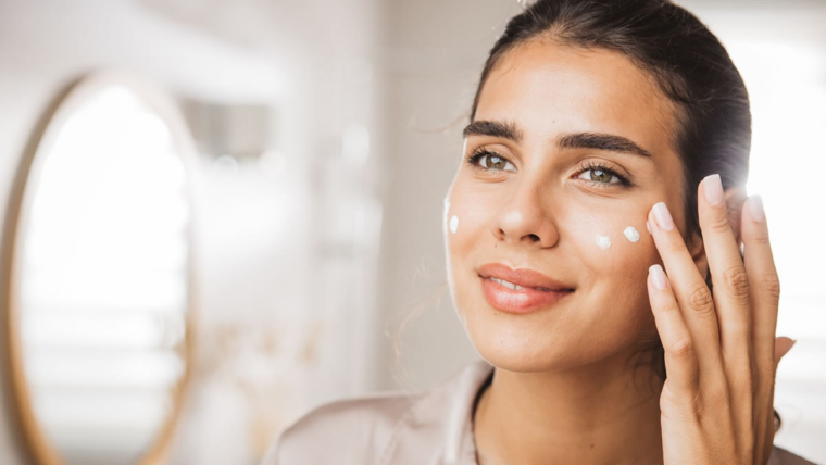Mulher montando uma rotina de cuidados com a pele usando produtos de skincare